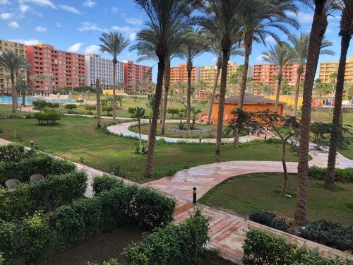 a park with palm trees and buildings in the background at Golf Porto Marina El Alamein studio Aqua 52111 in El Alamein