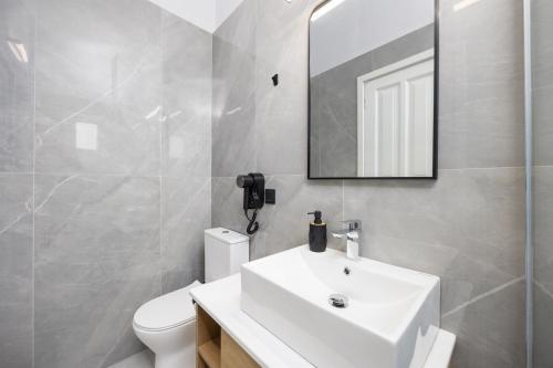 une salle de bain avec un lavabo blanc et un miroir dans l'établissement Kosmas Apartments, à Roda