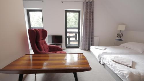 a bedroom with a bed and a chair and a coffee table at Willa Uroboros in Szklarska Poręba