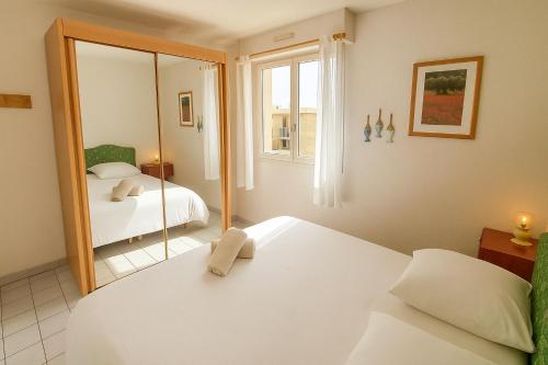 a bedroom with two beds and a mirror at Echappée Marine - Plage du Grau-du-Roi in Le Grau-du-Roi