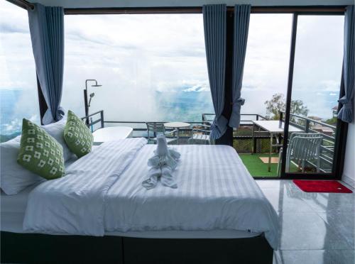 a bedroom with a bed and a large window at น่านฟ้าธาราหมอก ภูทับเบิก in Ban Tha Kok Hai