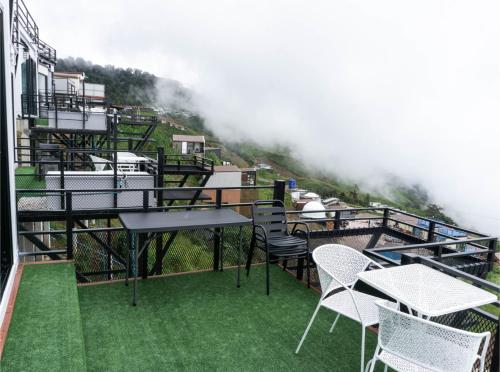 a balcony with chairs and tables on a mountain at น่านฟ้าธาราหมอก ภูทับเบิก in Ban Tha Kok Hai