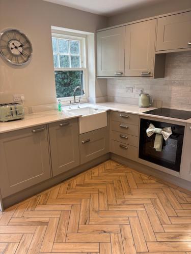 cocina con armarios blancos y suelo de madera en The Annexe, The Walled Garden- Nr Bicester Village, en Bicester
