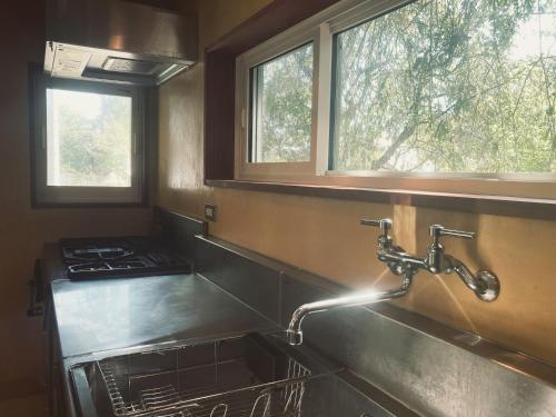 - un évier de cuisine avec un robinet et 2 fenêtres dans l'établissement 森と温もりに包まれる長野飯綱高原の隠れ宿ヴァイオレットハウス, à Nagano