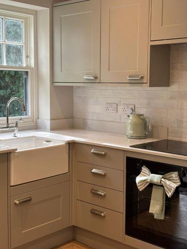 a kitchen with white cabinets and a sink at The Annexe, The Walled Garden- Nr Bicester Village in Bicester