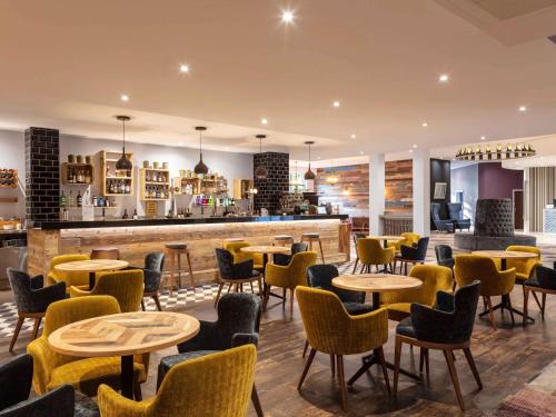 Un restaurante con mesas y sillas y un bar. en Novotel Newcastle Airport, en Newcastle