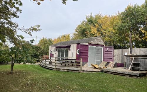a purple shed with chairs on a deck in a yard at Purple CargoPod at Lee Wick Farm Cottages & Glamping in Clacton-on-Sea