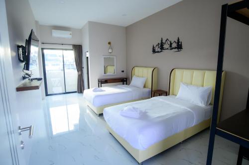 a bedroom with two beds and a sliding glass door at The Breezy Hotel in Muaklek