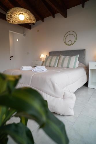a bedroom with a bed with white sheets and pillows at Tangerina Apart Hotel - Villa Gesell in Villa Gesell