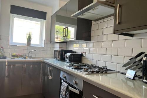a kitchen with a stove top oven next to a sink at Central 4-Bed House - Parking Patio Garden Wifi in Lincoln
