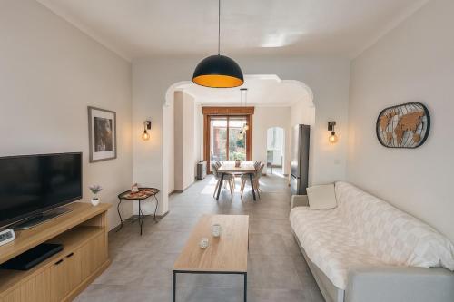 ein Wohnzimmer mit Sofa und Fernseher in der Unterkunft Maison cosy avec terrasse et jardin - Aéroport gare in Charleroi