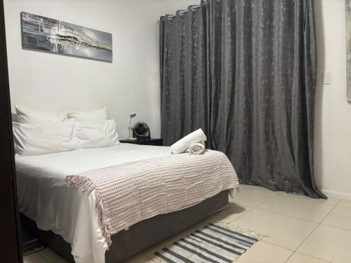a bedroom with a bed and a gray curtain at Urban Park K001, Umhlanga Rocks in Durban