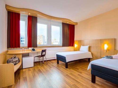 ein Hotelzimmer mit zwei Betten und einem Schreibtisch in der Unterkunft ibis Luzern Kriens in Luzern