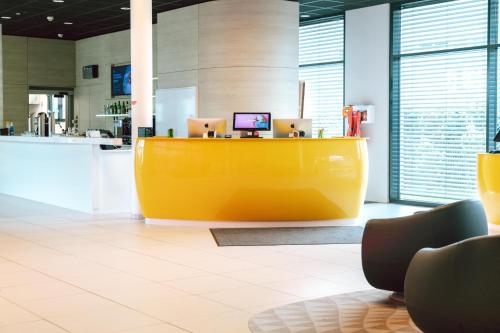 an office with a yellow desk with two laptops on it at Prize by Radisson, Munich Airport in Hallbergmoos