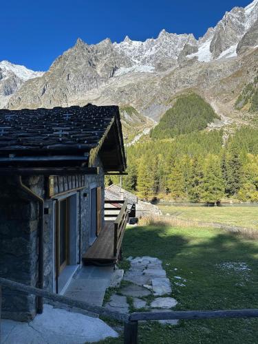a building with a bench in front of a mountain at Baita Val Ferret CIR 0246 in Courmayeur