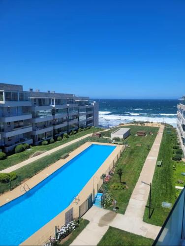 an image of a swimming pool with the ocean in the background at Apartamento primera linea El Tabo in El Tabo