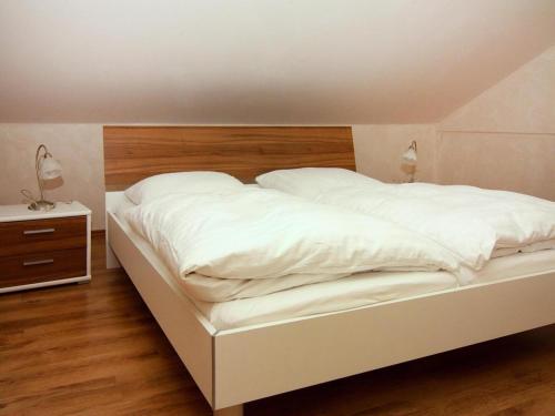 a white bed with a wooden headboard in a bedroom at Ferienpark Markgrafenheide in Markgrafenheide