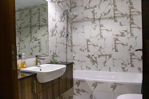 a bathroom with a sink and a bath tub at Marina Retreat Stylish One Bedroom by Hala Homes in Ras al Khaimah