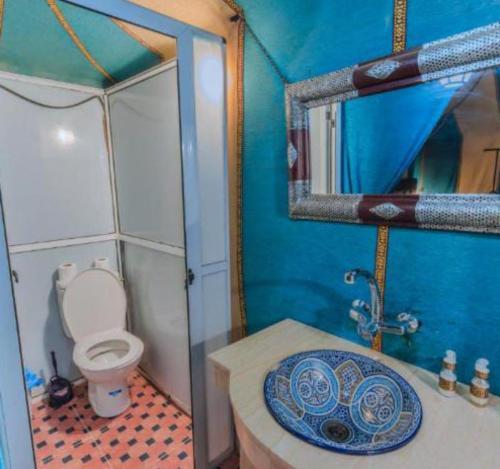 a bathroom with a toilet and a sink and a mirror at Desert Marhaba luxury Camp in Merzouga