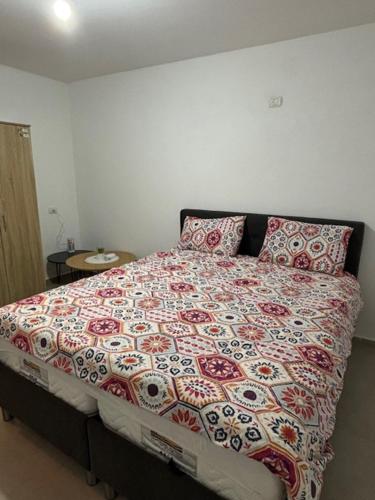 a bedroom with a bed with a floral bedspread and pillows at סוויטת הגן השקט- סוויטה מושלמת במעלות in Ma'alot Tarshiha