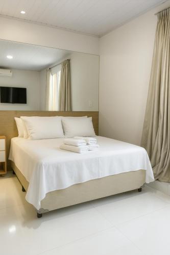 a bedroom with a white bed with towels on it at Hotel Pousada Litorânea in Tijucas