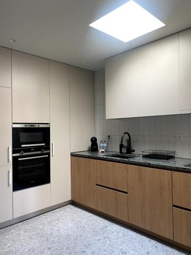 a kitchen with white cabinets and a black oven at Misericórdia Garden Homes in Vila do Conde
