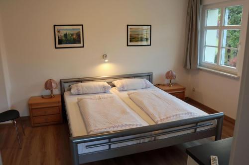 a bedroom with a bed with two lamps and a window at Ferienwohnung im Kasperhaus in Hohnstein