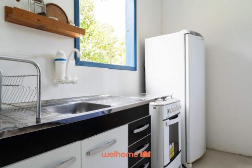 une cuisine avec un évier et un réfrigérateur dans l'établissement Kitnet em Aldeia Velha com piscina e churrasqueira, à Aldeia Velha