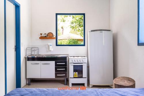 a kitchen with a stove and a refrigerator at Kitnet em Aldeia Velha com piscina e churrasqueira in Silva Jardim