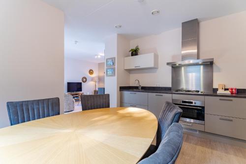 a kitchen and dining room with a wooden table and chairs at Duinhof Klein Dishoek - Appartementen onder aan de duinen, in het centrum met terras in Dishoek