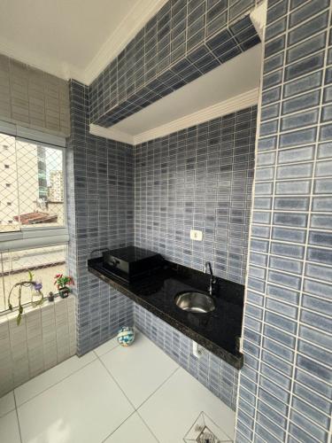 Apartamento Praia Grande caiçara في برايا جراندي: حمام به جدران من البلاط الأزرق ومغسلة