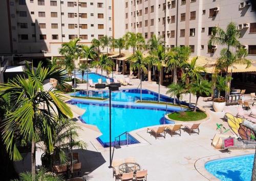 a view of a pool with palm trees and a building at Boulevard Suite in Caldas Novas