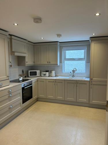 a kitchen with white cabinets and a sink and a window at Derry City Apartment in Derry Londonderry