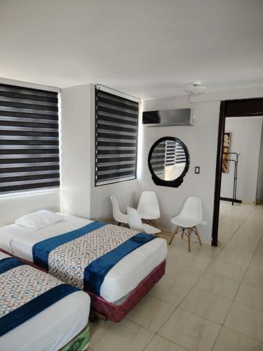 a bedroom with two beds and a mirror and chairs at HOTEL 2 Mares PANAMA in Panama City