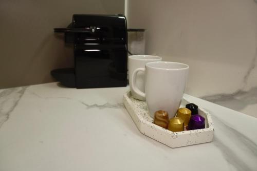 two cups sitting on a counter next to a coffee maker at Elite Glow Studio in Roşu