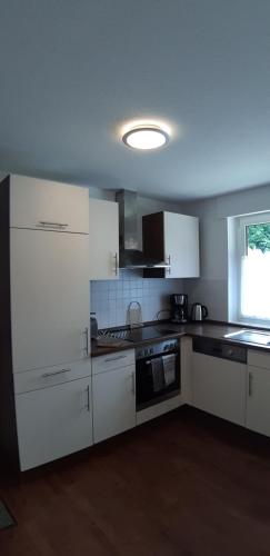 a kitchen with white cabinets and a stove top oven at Bilstein RE04 in Sögel