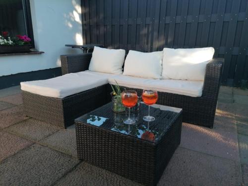 un canapé en osier avec deux verres à vin sur une table dans l'établissement Häuschen in grüner Idylle, à Berggiesshübel