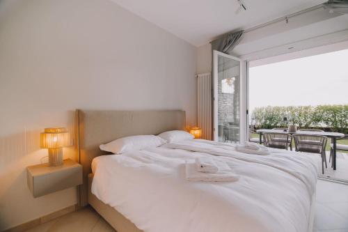 ムッソにあるExclusive Garden Apartment with Lake View & Poolの白いベッドと大きな窓のある寝室