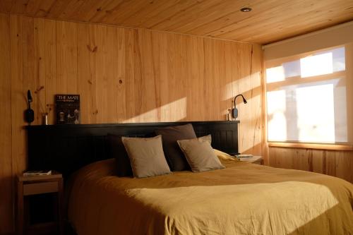 a bedroom with a bed with a wooden wall at Iar Residencia in El Chalten