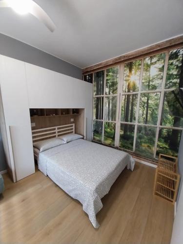 a bedroom with a bed and large windows at Litte Sweet Home - Abbiategrasso città in Abbiategrasso