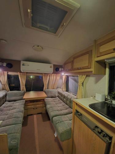 a living room with a couch and a kitchen in an rv at The Box Promkiri (เดอะบ๊อค พรหมคีรี) in Ban Pak Ram