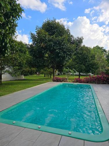 a swimming pool in a yard with trees and flowers at The Box Promkiri (เดอะบ๊อค พรหมคีรี) in Ban Pak Ram