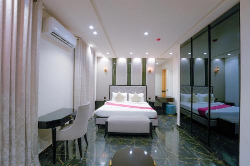 a hotel room with two beds and a desk at La Maison Royale Hotel in Lahore