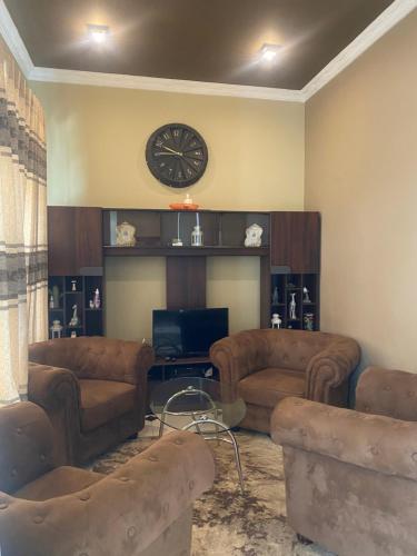 a living room with couches and a clock on the wall at Seventh Heaven Villa in Hakgala