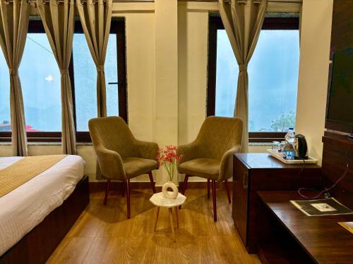 a hotel room with two chairs and a bed and windows at Hotel Mini Switzerland In Dalhousie in Dalhousie