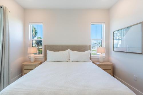 een slaapkamer met een wit bed en 2 ramen bij Tranquil Daze by Sun Palace Vacations in Fort Myers Beach