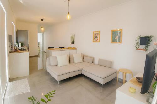 a living room with a white couch and a tv at Sunny Penthouse with Large Terrace in Marsaxlokk