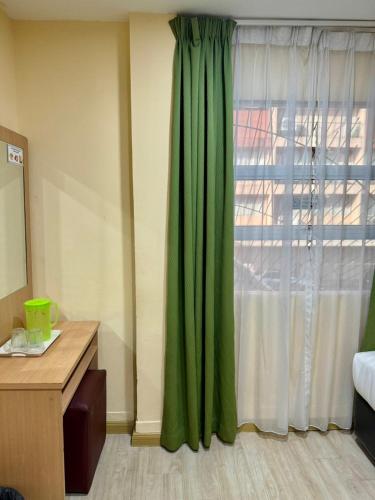 a room with a green curtain and a window at Labuan Avenue Hotel in Victoria