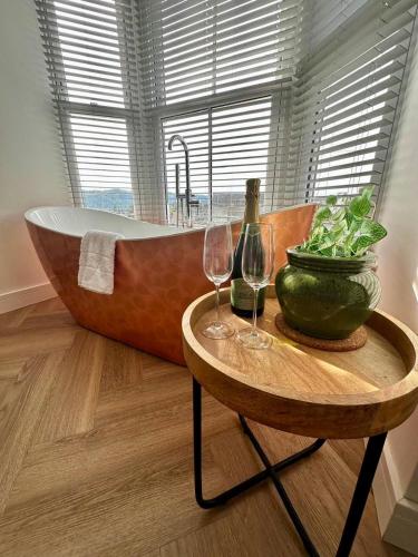 a bathroom with a tub and two wine glasses on a table at Luxury Pet-Friendly 2 Bed Retreat in Central Bowness with Copper Roll-Top Bath & Sun Terrace in Bowness-on-Windermere