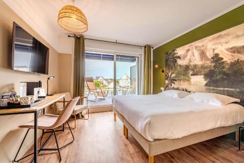 a bedroom with a bed and a desk and a window at The Originals Boutique, Hôtel Spa Le Triton, Roscoff in Roscoff
